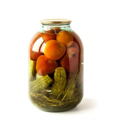 Salted cucumbers and tomatoes in a glass jar isolated on white