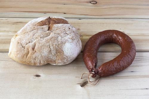 A Cracow sausage and a hearth bread on a wooden table