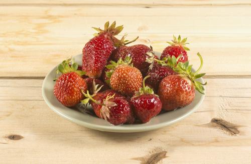 Fresh strawberry on a green ceramic plate on a wooden table