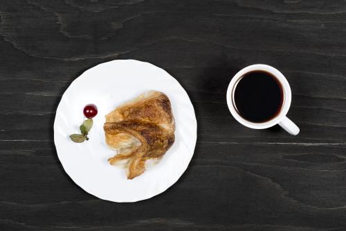 Cup of tea with puff pastry on a black wooden surface