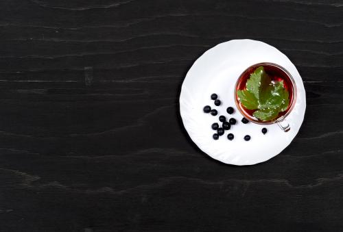 Black currant tea on a white dish on a black wooden surface