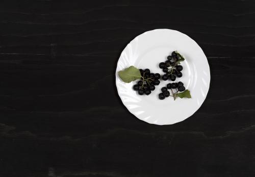 Black ashberry on a white dish on a black wooden surface