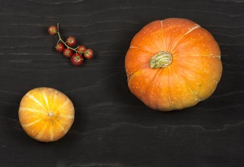 Ripe orange pumpkins and red tomatoes on a black wooden surface
