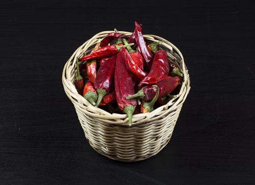 Red pepper in a basket on black wooden surface