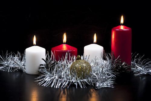 Burning candles on black background with garland