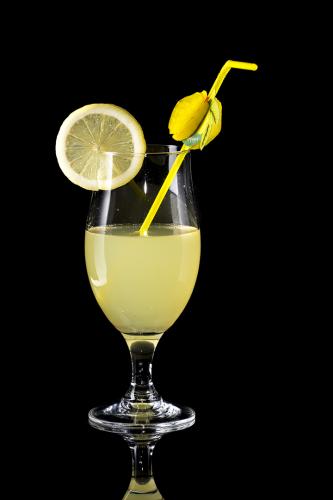 Glass of lemonade with bendie on black mirror background