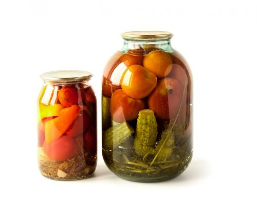 Salted cucumbers and tomatoes in glass jars isolated on white
