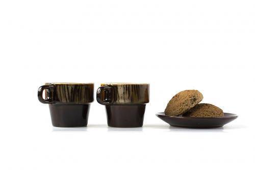 Two ceramic cups with cookies on a dish isolated on white