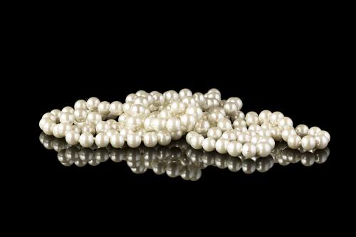 Pearl necklace on a black mirror surface