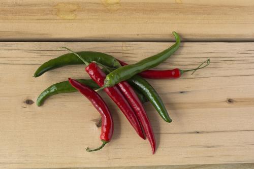 Red and green hot chilly peppers on a wooden table. Top view