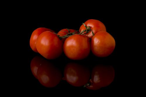 Red fresh tomatoes on a black mirror background