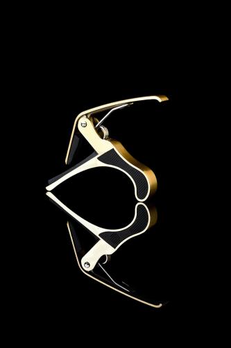 Golden capodaster on a black mirror background