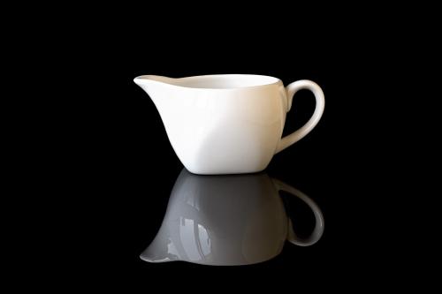 White gravy boat on a black mirror background