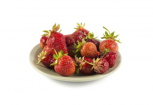 Fresh strawberry on a green ceramic plate isolated on white