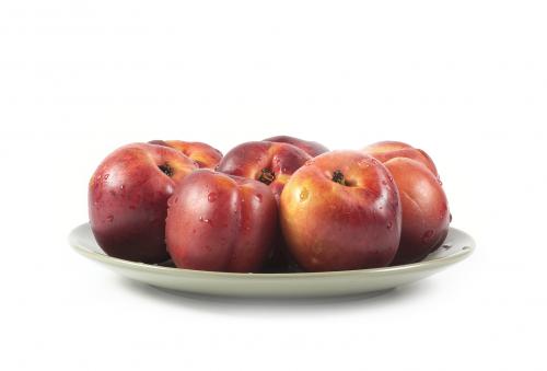 Ripe red peaches on green ceramic plate isolated on white
