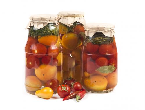 Canned salted tomatoes in glass banks isolated