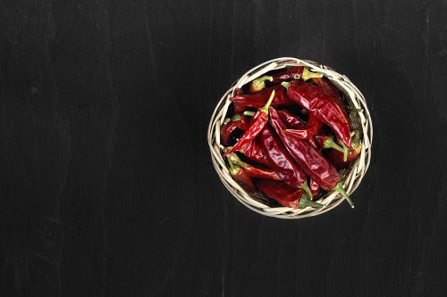 Red pepper in a basket on black wooden surface