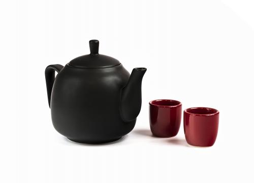 Black ceramic teapot and two red cups isolated on white