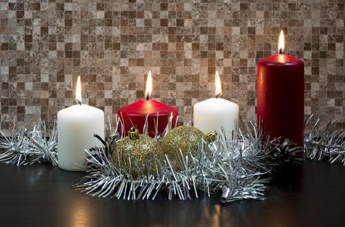 Burning candles on mosaic background with garland