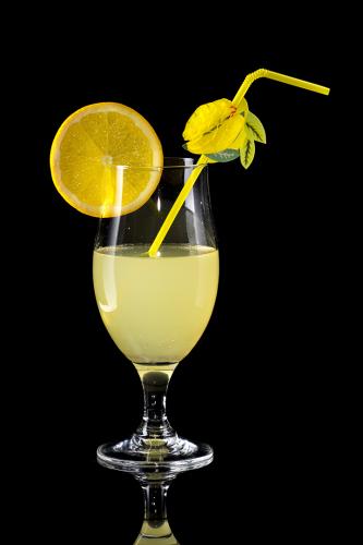 Glass of lemonade with bendie on black mirror background