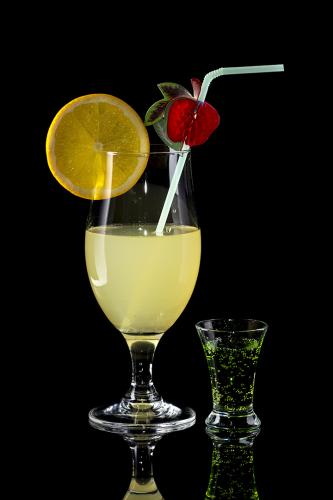 Glass of lemonade with bendie on black mirror background